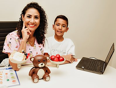 Mônica em atendimento com um menino, com alimentos sobre a mesa