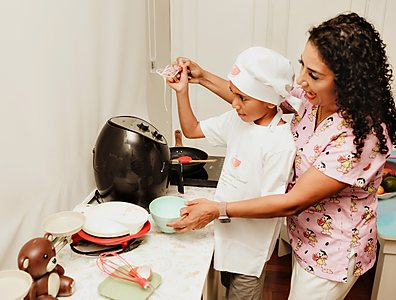 Mônica cozinhando com uma criança de touca de chef