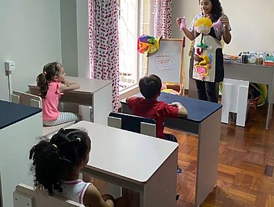 Mônica em atividade em grupo com crianças sentadas às mesinhas