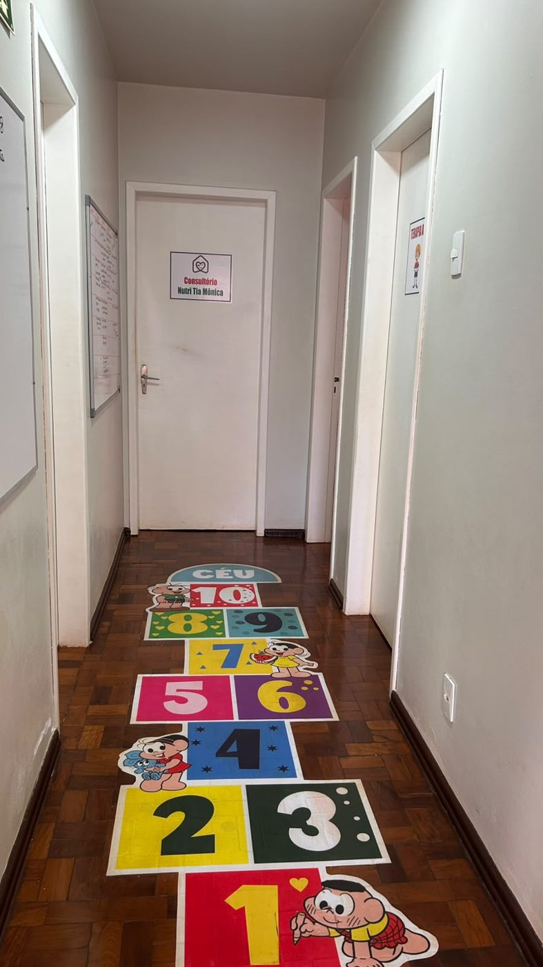 Corredor com amarelinha desenhada no chão e portas das salas