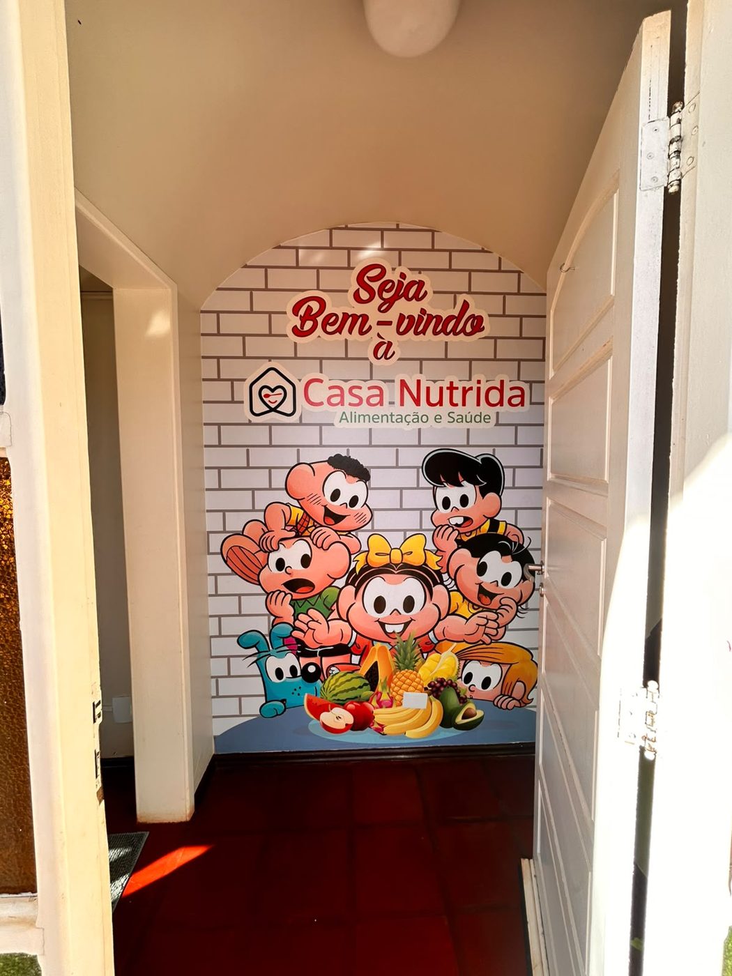 Porta de entrada com painel 'Seja bem-vindo à Casa Nutrida' e a Turma da Mônica