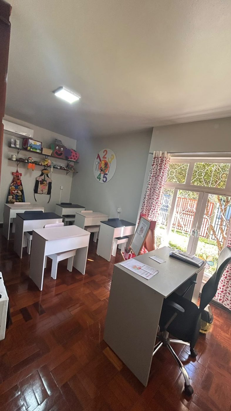 Sala da escolinha com mesinhas brancas e cadeiras
