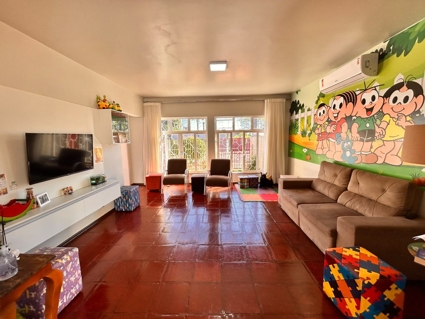 Sala de estar com sofá, TV e pintura da Turma da Mônica